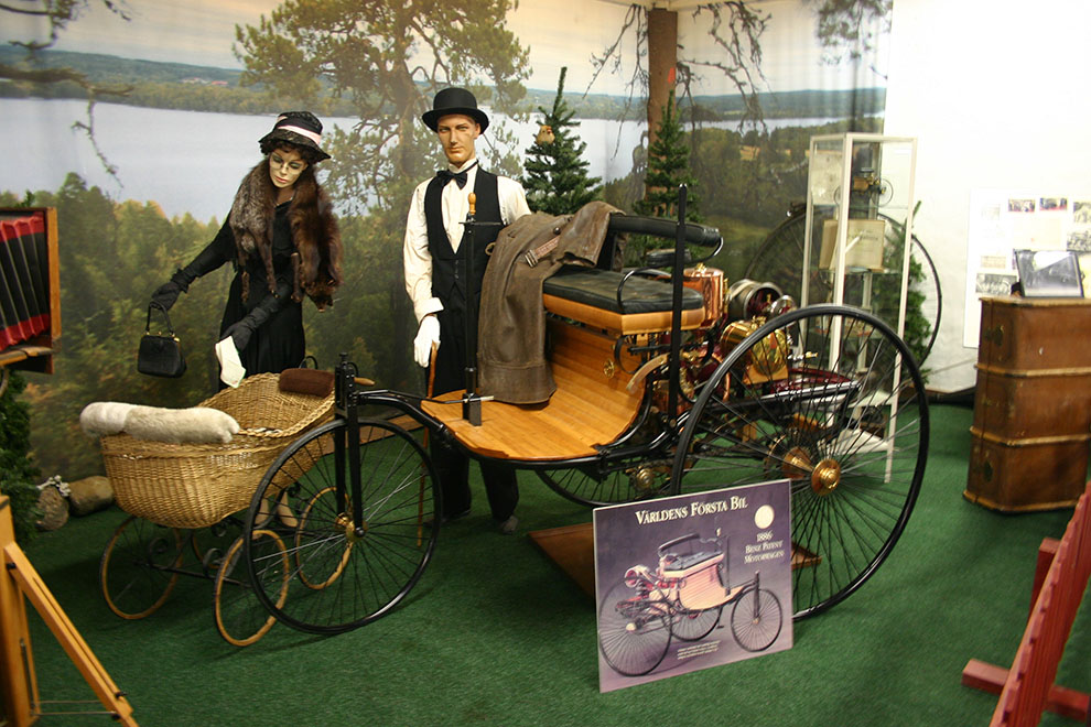 En autentisk kopia av 1886 Benz Motorwagen, världens första bil. Historien låter berätta att Karl Benz var nöjd över konstruktionen och skulle testköra dagen efter. Men då var bilen borta! Det finns (och har tydligen alltid funnits) ”förvetna” kvinnor. Fru Benz hade snott bilen utan makens vetskap och företagit en längre tur!