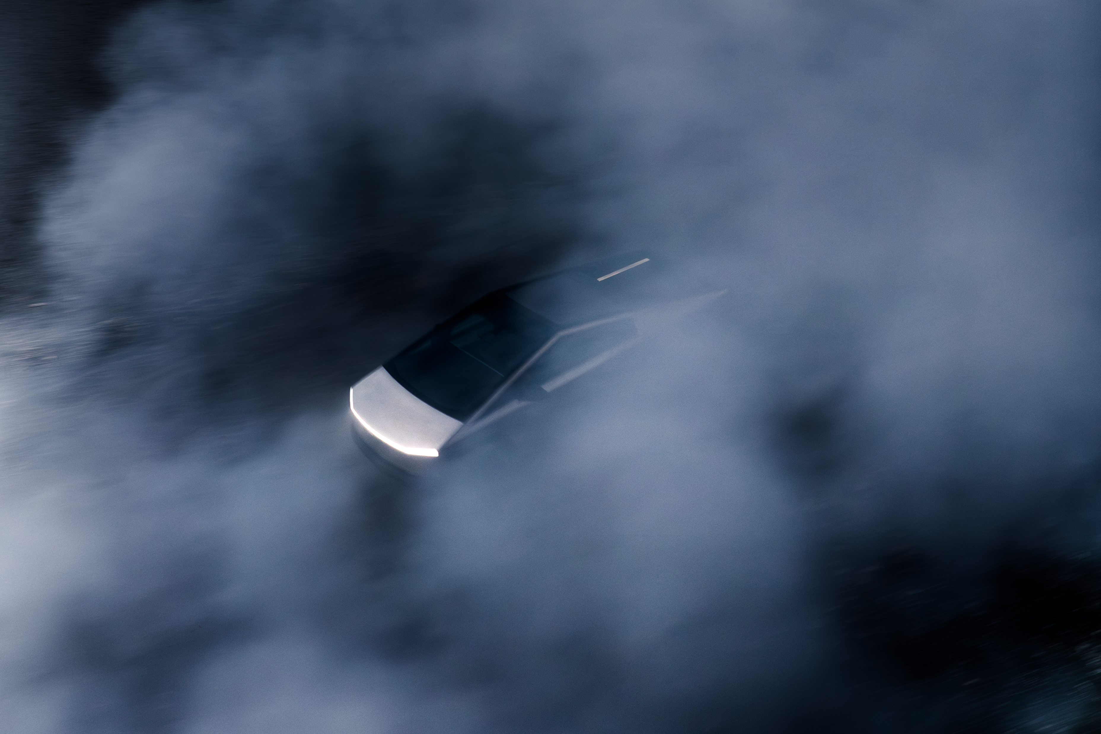 En suddig bild underifrån och bakifrån på en Tesla Cybertruck i vitt ljus och rök eller dimma.