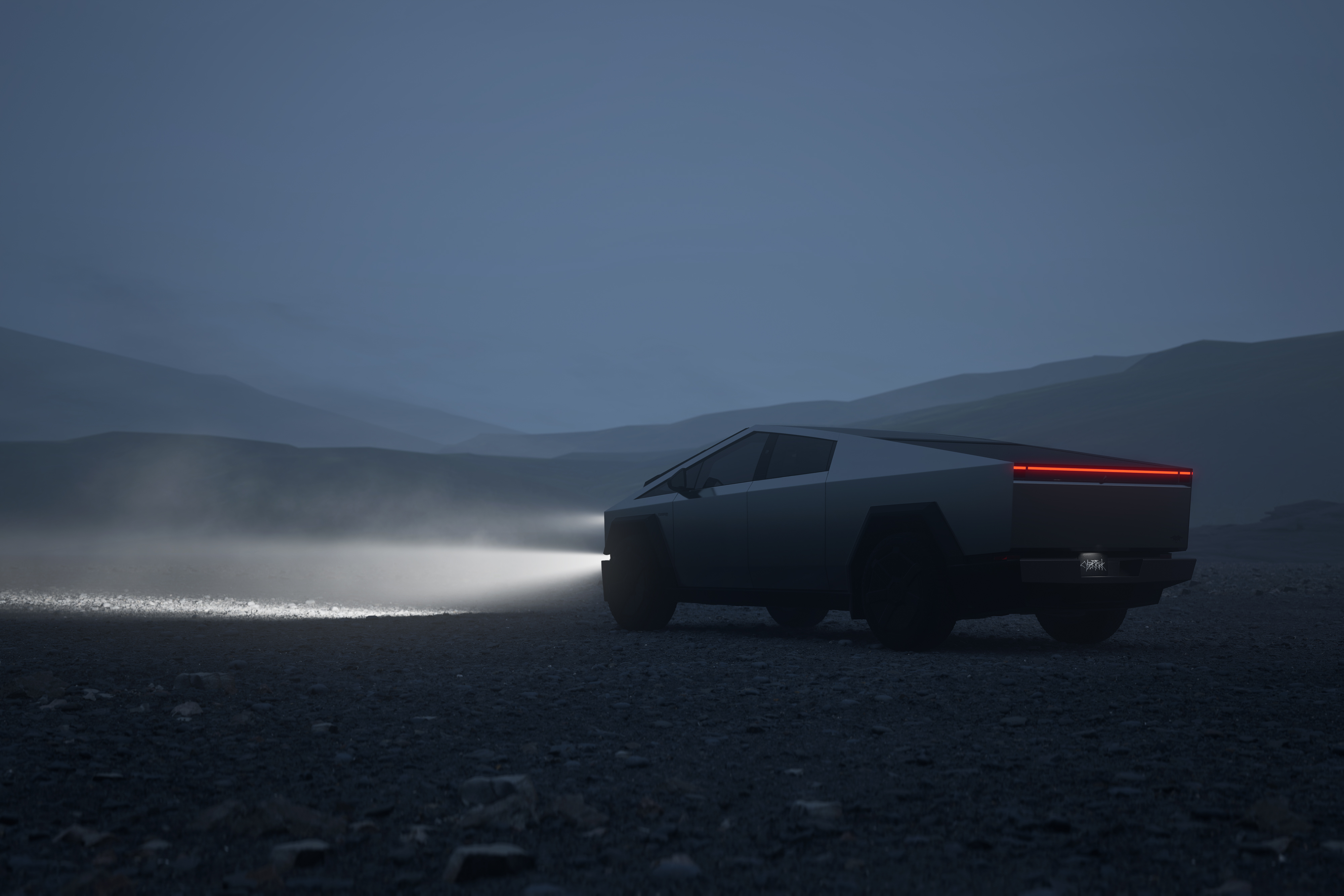 En Tesla Cybertruck står i profil från vänster sida med strålkastarna tända i ett mörkt, disigt landskap.