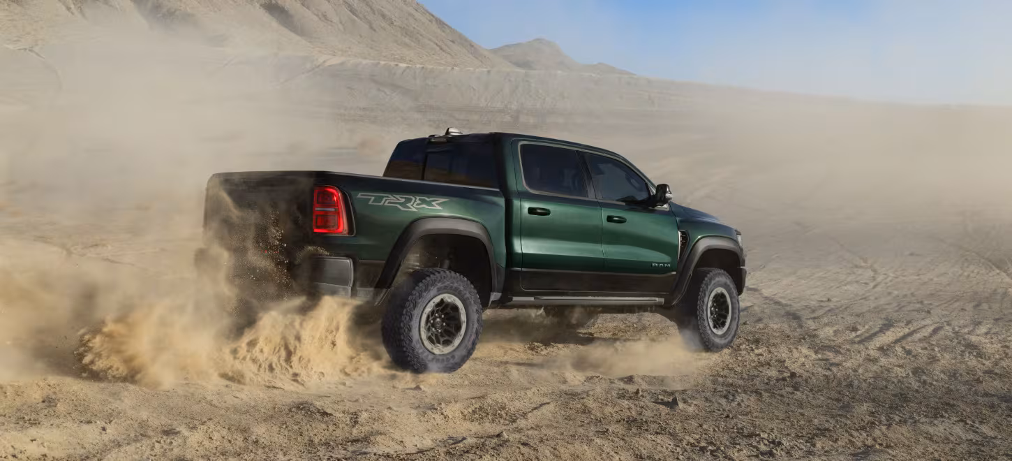 Nya Ram 1500 SRT TRX i dess naturliga element – en dammig terrängmiljö. Bilen har en grön-svart färg med röd baklykta och stora offroad-hjul.