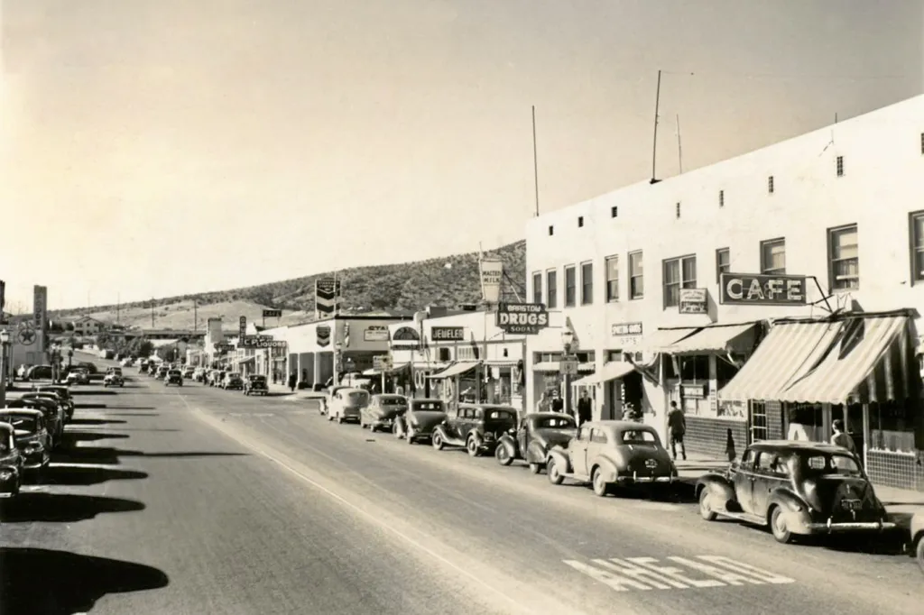 Möt Barstow, Kalifornien år 1947, en klassisk Route 66-ort med livlig gata, gamla bilar och karakteristiska butiksfasader.