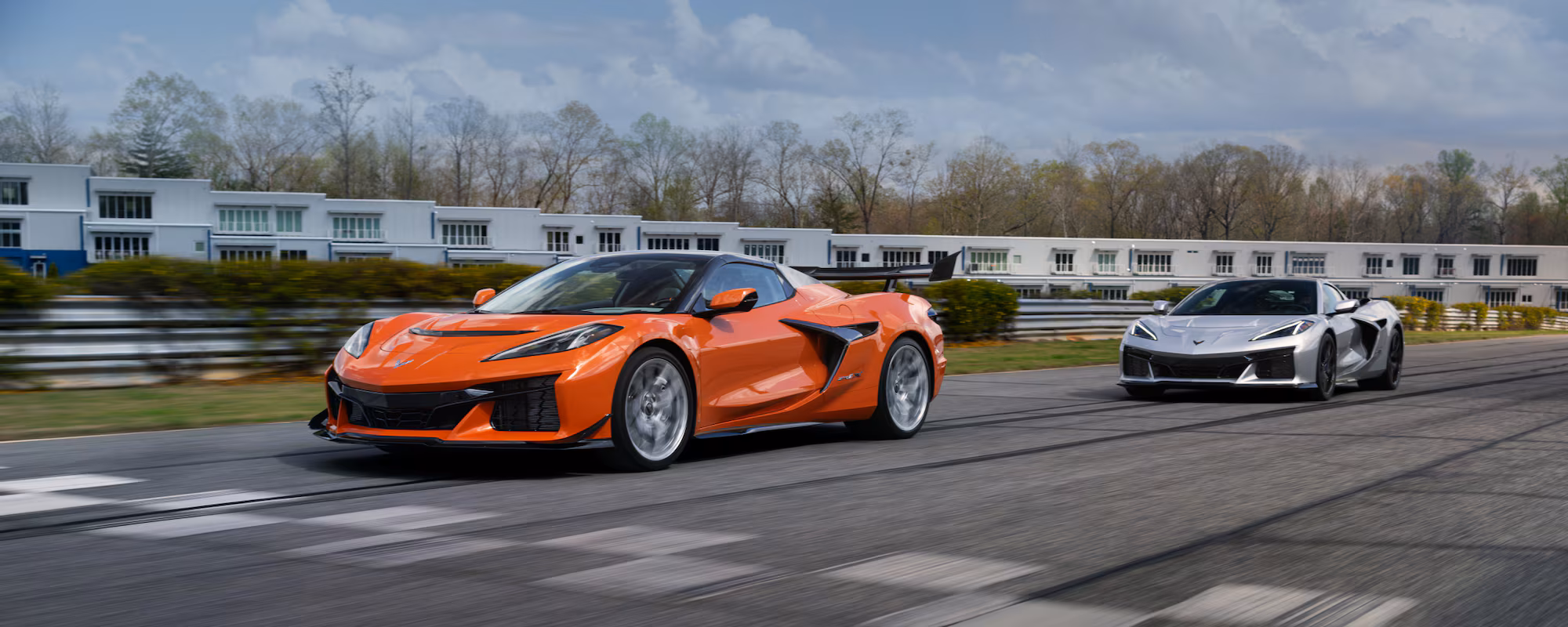 Den nya Corvette ZR1X:en i orange, med en tidigare generation Corvette i silver intill, redo att visa vad den går för på banan.