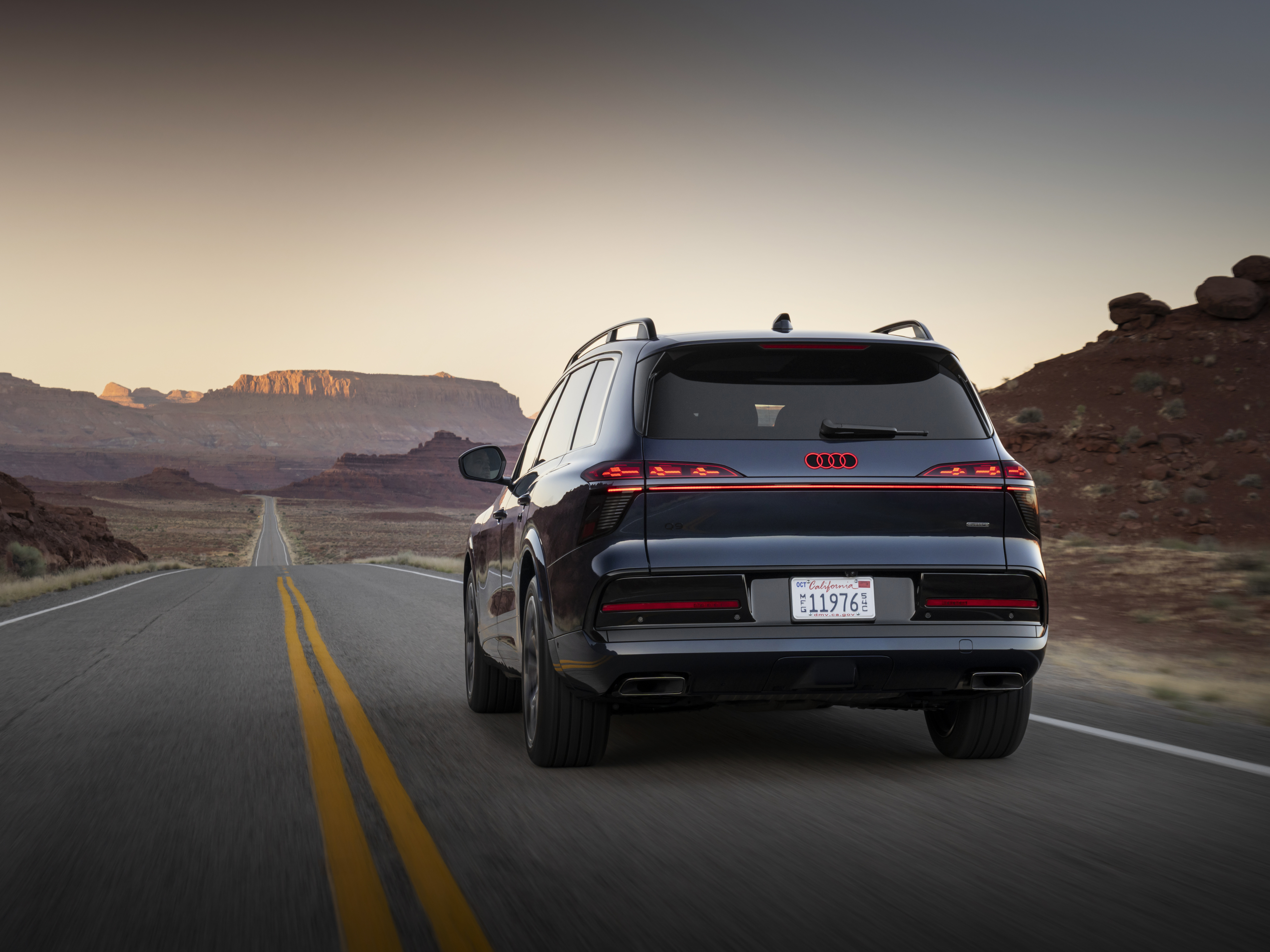 Den mäktiga baken på Audi Q9, med de karaktäristiska bakljusen, på en öppen väg.
