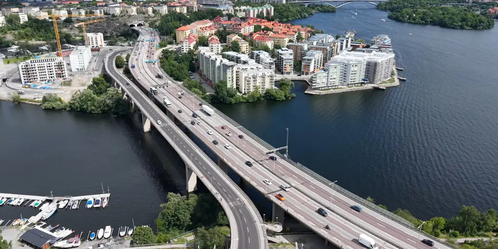 Essingeleden från ovan med den täta trafiken som passerar förbi bostadsområdena vid Lilla Essingen och Fredhäll.