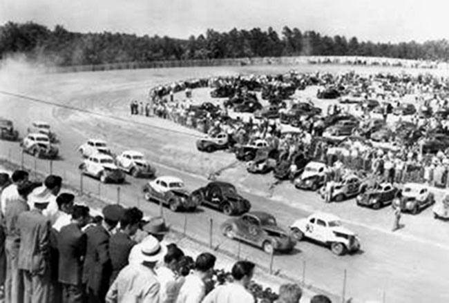 Bilden är från Lakeview Speedway i North Carolina den 6 juni 1949. Leder gör Tim Flock i bil nr 90, tätt följd av Glenn Dunnaway i bil nr 9.