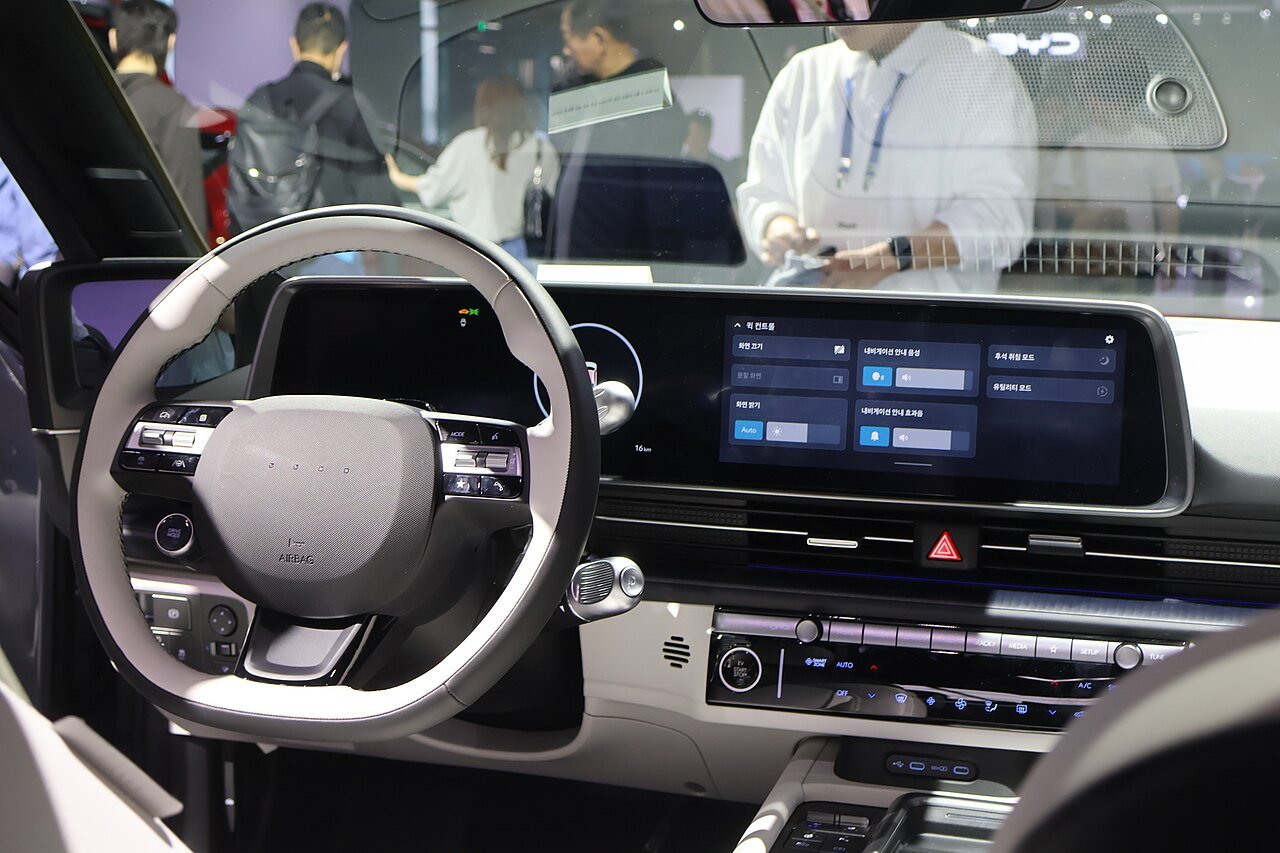 Förarplatsen i Hyundai Ioniq 6 med den breda skärmpanelen. Äldre mjukvara är enligt InsideEVs genomgång en av bilens svagare sidor. Foto: Treeinkr, CC BY-SA 4.0.
