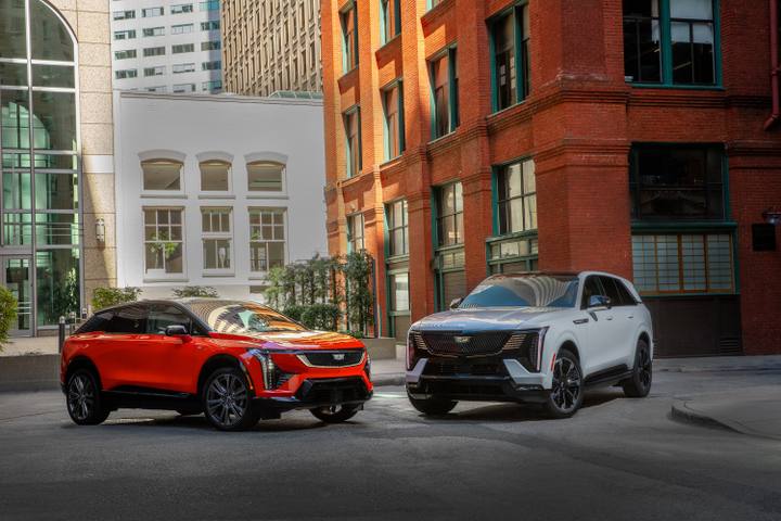 Två Cadillac Escalade IQ, en i rött och en i vitt, visar upp modellens kaxiga men eleganta design på stadsgatan.