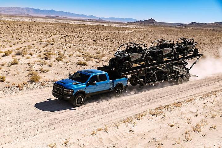 En RAM-pickup drar en stor trailer med flera terrängfordon genom öknen. Att hantera sådana ekipage kräver rätt körkortsbehörighet, särskilt i Sverige.