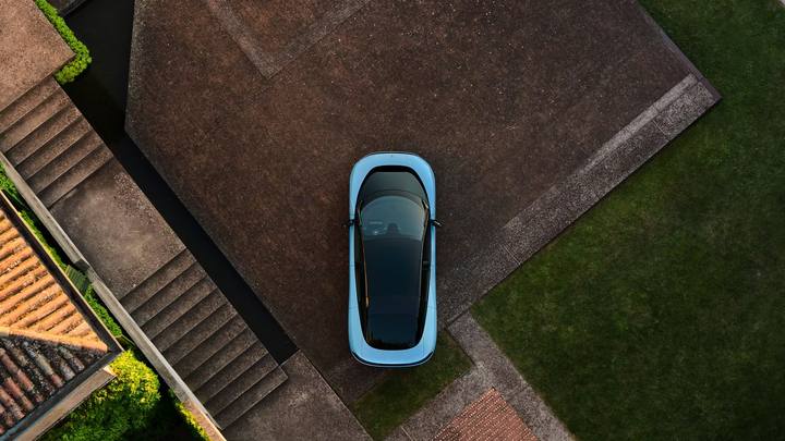 Ferrari Luce sedd från ovan, parkerad på en modern uteplats. Den ljusa färgen och det svarta taket skapar en slående kontrast.