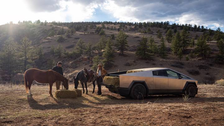 Cybertruckens flak fyllt med höbalar, flankerad av hästar och människor i cowboyattire. En typisk amerikansk scen – långt från svenska förhållanden.