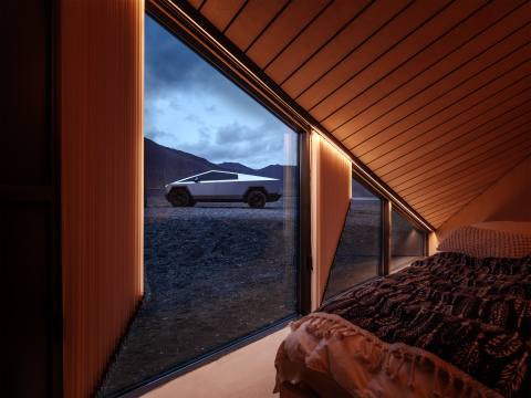 Cybertrucken syns här från insidan av en modern stuga. Dess markanta design smälter in i det dramatiska landskapet, men dess storlek är svår att få grepp om utan en referenspunkt.