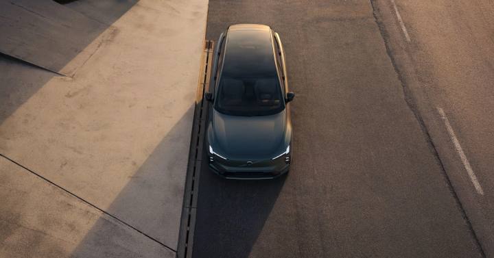 Från ovan ser vi nya Volvo EX60 i en matt mörkgrön lack, elegant parkerad intill en trottoarkant. Den moderna designen framhävs.