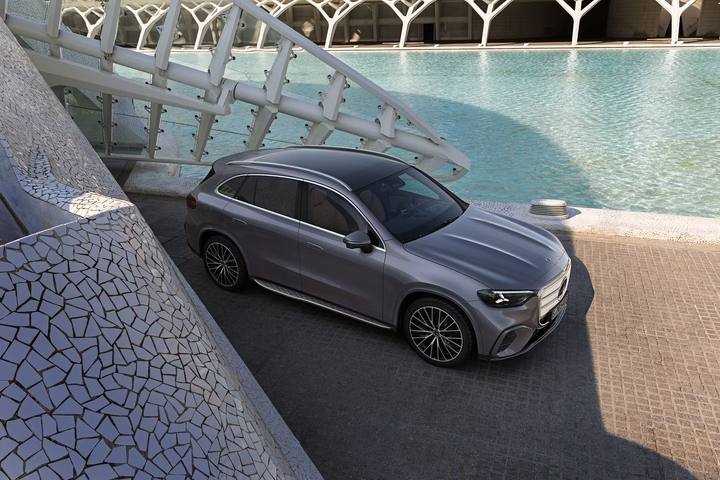 Den nya Mercedes GLC, fotograferad snett framifrån, med en modern arkitektur och vatten i bakgrunden.