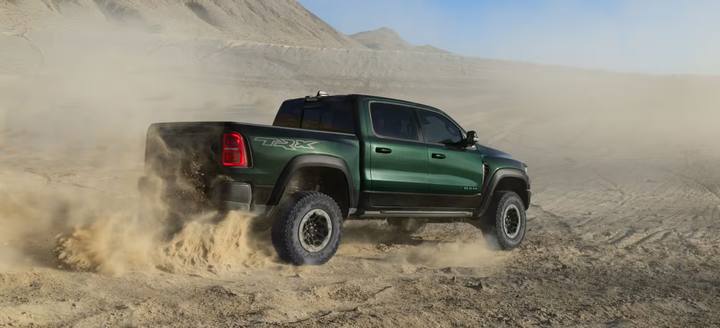 Nya Ram 1500 SRT TRX i dess naturliga element – en dammig terrängmiljö. Bilen har en grön-svart färg med röd baklykta och stora offroad-hjul.