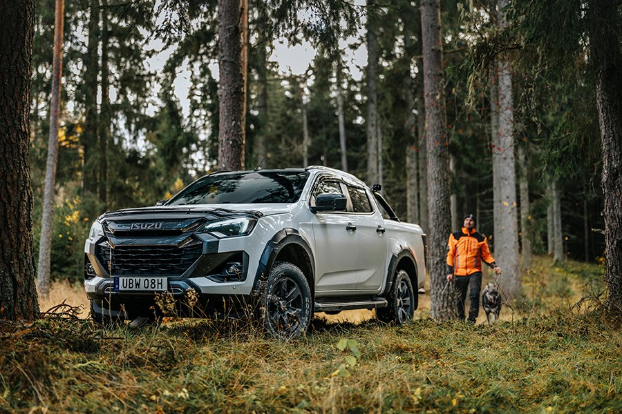 Isuzu D-Max ute i skogen med en förare och hund. Bilen är ett bra budgetalternativ bland "arbetshäst"-pickuperna.