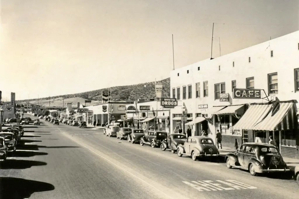 Möt Barstow, Kalifornien år 1947, en klassisk Route 66-ort med livlig gata, gamla bilar och karakteristiska butiksfasader.