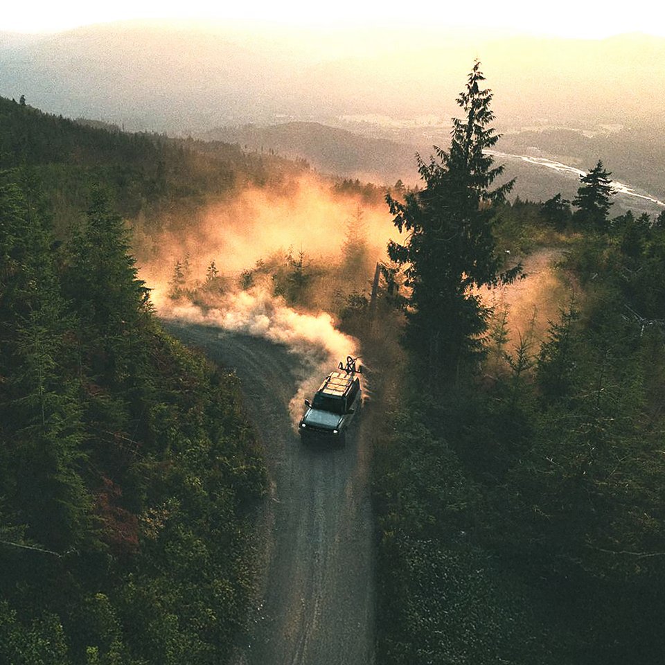 Ford Bronco i sin naturliga miljö, genererar ett imponerande dammoln på en grusväg bland bergens grönska.